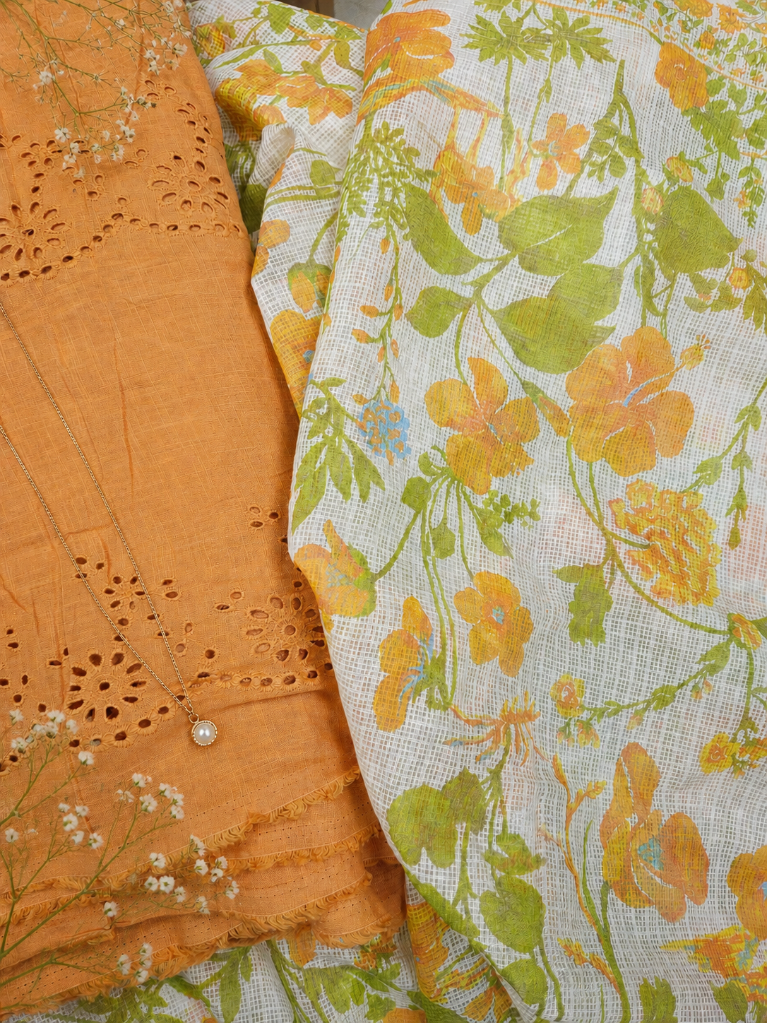 Close-up of orange fabric with intricate cut-out design and floral-patterned fabric.